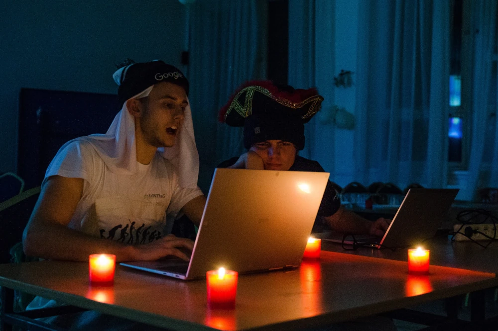 Vedúci sústredenia KSP debugujú programy účastníkov v tme pri sviečkach