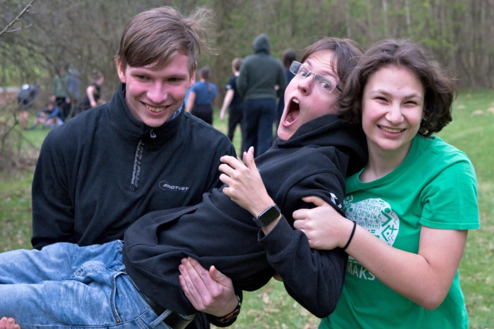 Ǔčastníci sústredenia KSP prenášajú vedúceho na hre vonku